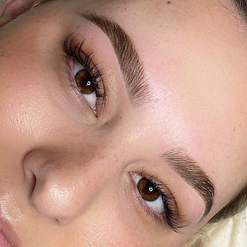 Close detail of softly shaded cosmetic tattoo brows framing brown eyes