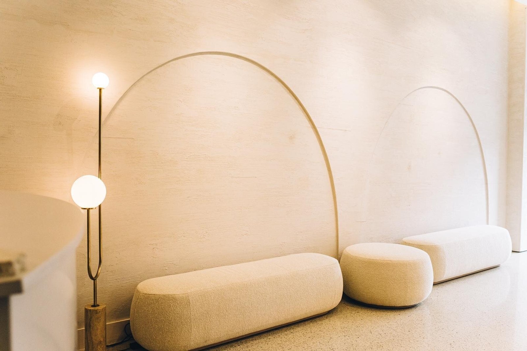 Inside the Suzie Mcintosh Brows studio in Toorak, with arched plaster walls, boucle seating and brass lighting